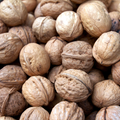 A close-up pile of whole walnuts in shell